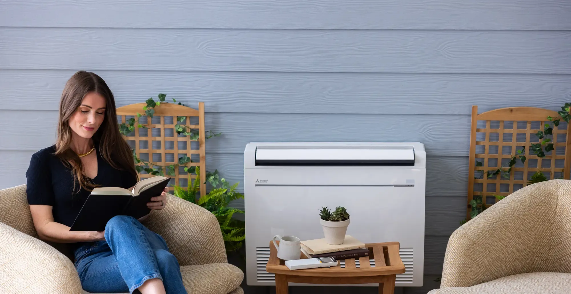 young woman sitting and reading with mitsubishi electric low-wall-mounted indoor unit to her right