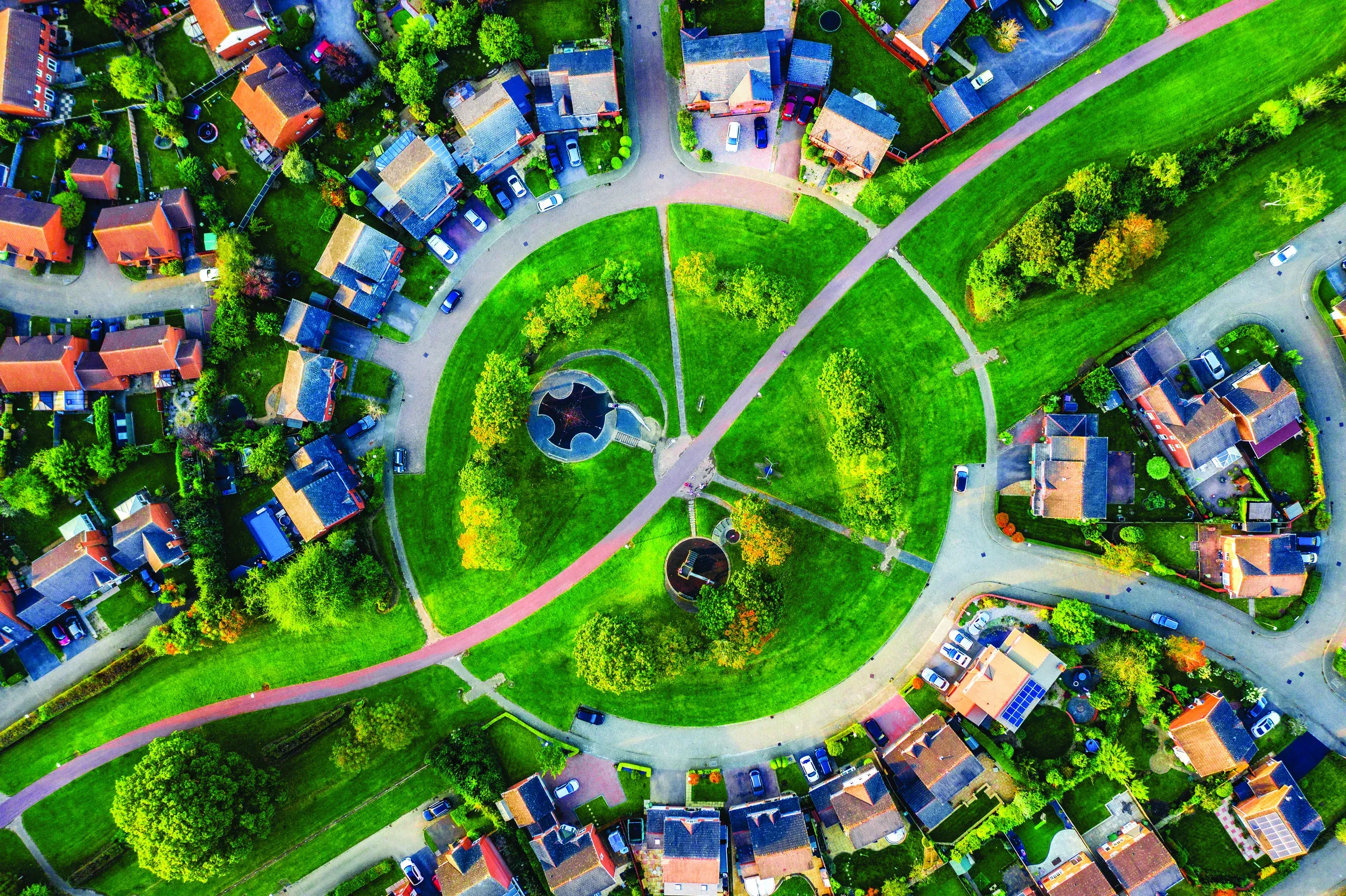 overhead aerial shot of green park with trees and walking paths surrounded by homes