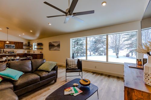 living room with open floor plan, leather sofa and large windows looking out into winter snow with trees